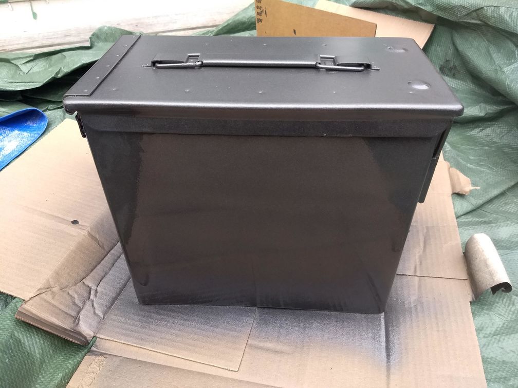 Shiny freshly-painted ammo can, sitting on cardboard