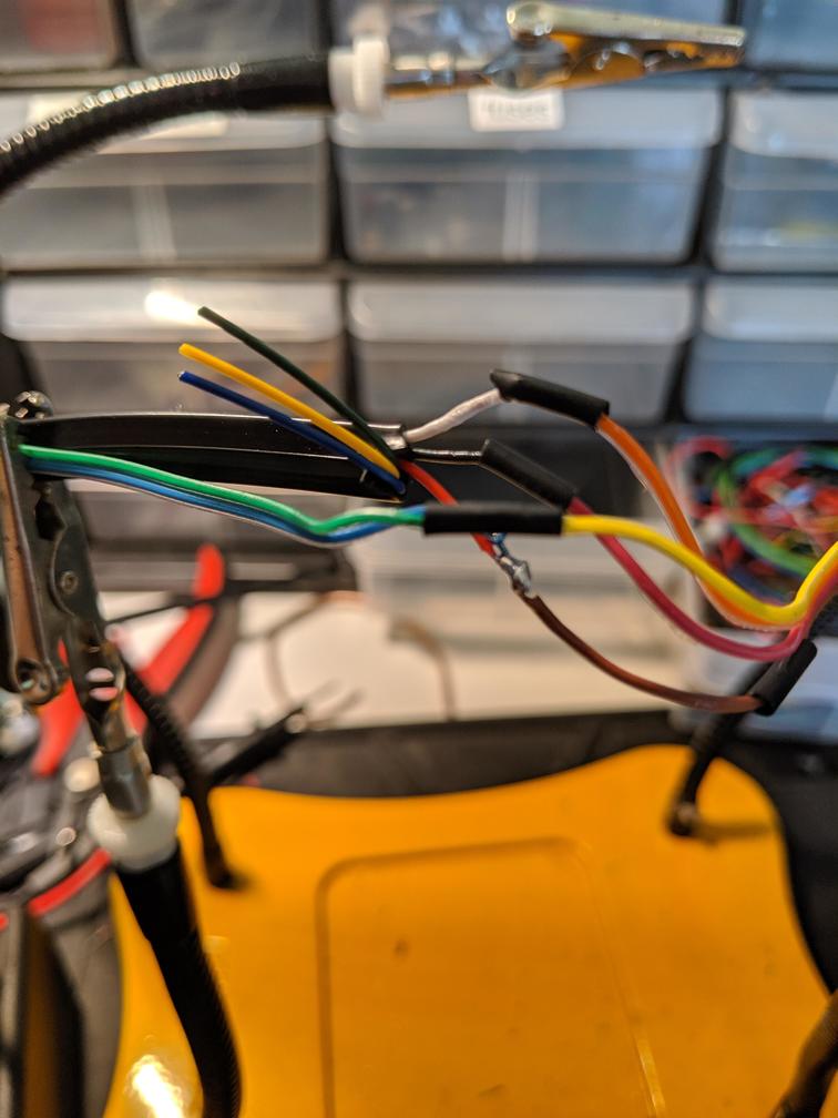 Wires held by a "helping hands" soldering tool, in the process of being spliced.
